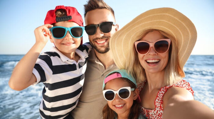 Happy family taking selfie on beach near sea. Summer vacation