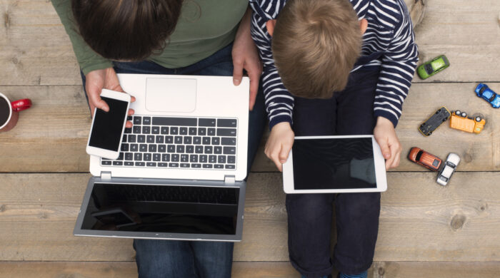 Top view image of young kid and his mother using online media Laptop, smartphone and digital tablet. Concept of mobile addiction.