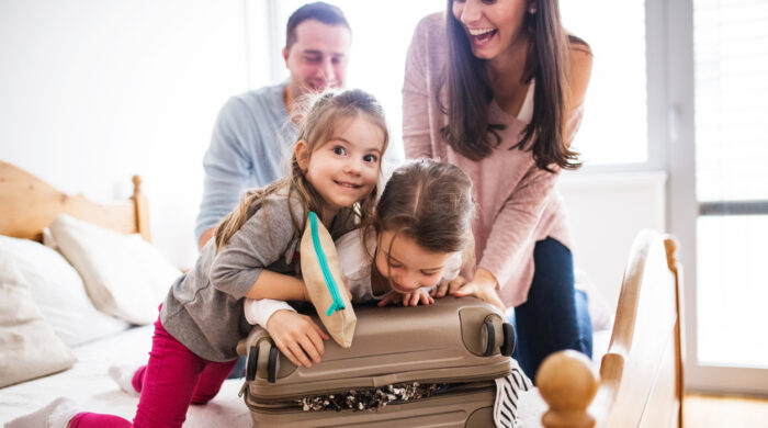 Portrait of a young happy family with two children packing for holiday at home.